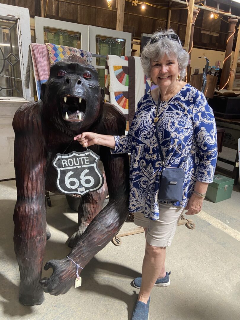A woman standing next to a wooden gorilla statue.