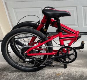 A red folding bike parked in front of a garage door.
